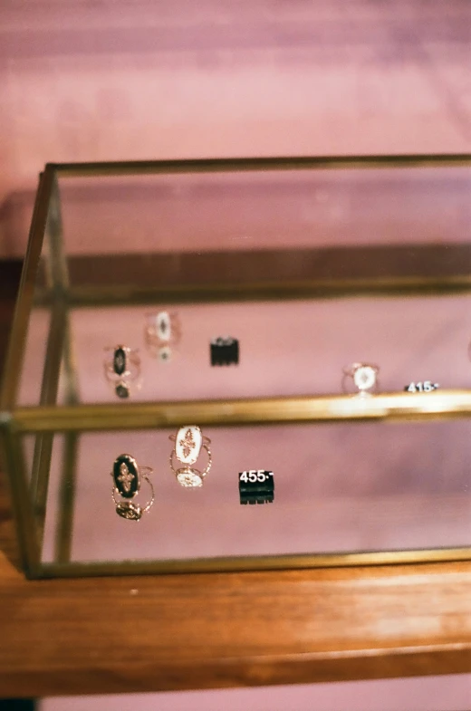 jewelry sitting in a glass display case next to a purple wall