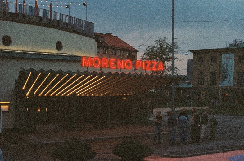 the neon sign above the building is advertising the pizza place