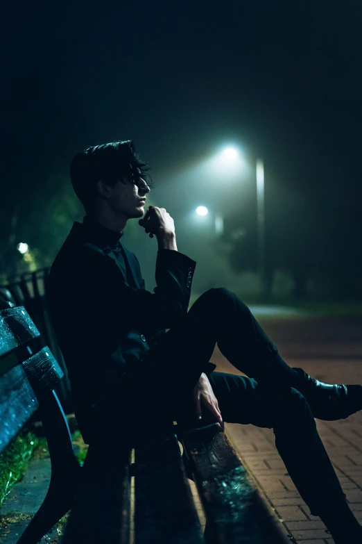 a person sitting on a park bench in the dark