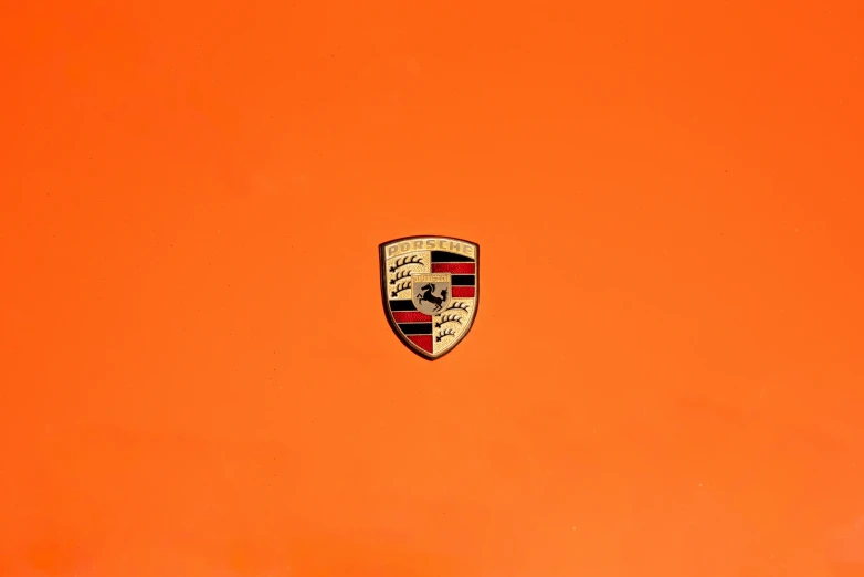 a close up image of a porsche emblem on an orange background