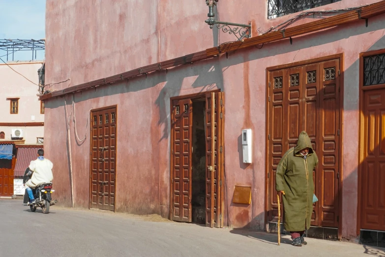 a person is walking in front of a pink building