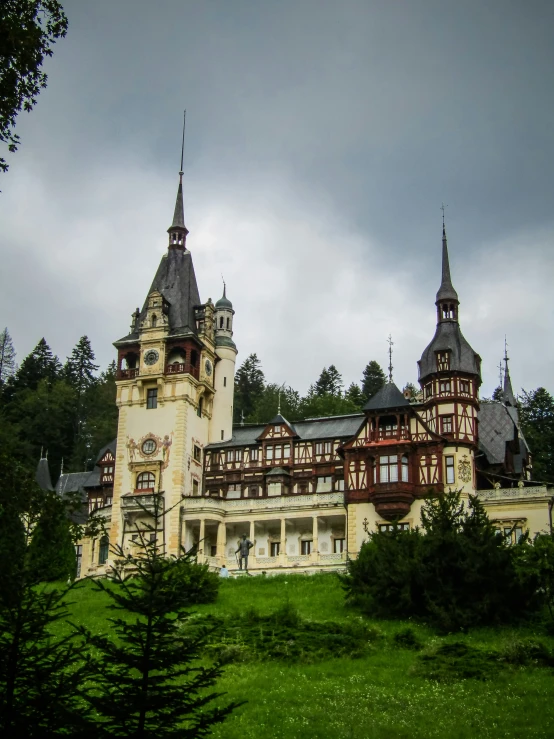 a large mansion with spires sits in the forest