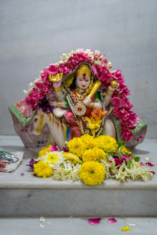 there is a statue of a hindu woman and a horse with flowers surrounding her