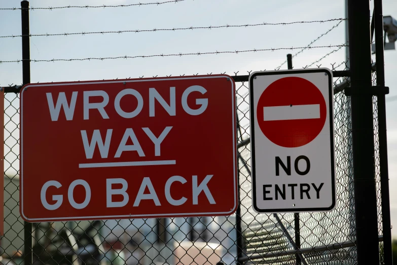 two road signs, one is for wrong way and the other reads go back