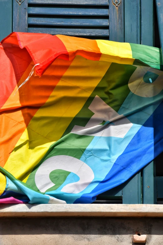 a rainbow flag sitting outside a building's window