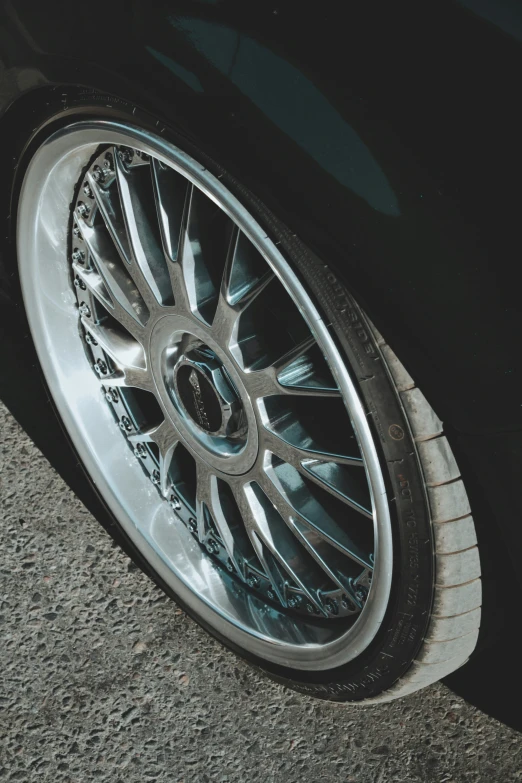an aluminum wheel of a car that is parked on the side of the road