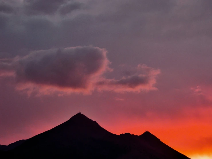 a large hill is against the background of sunset