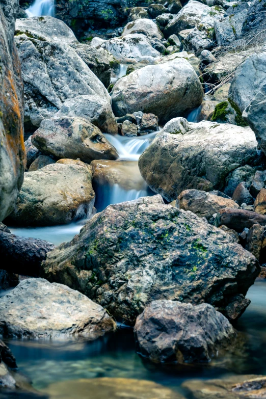 a river flows between a rock garden with small waterfall