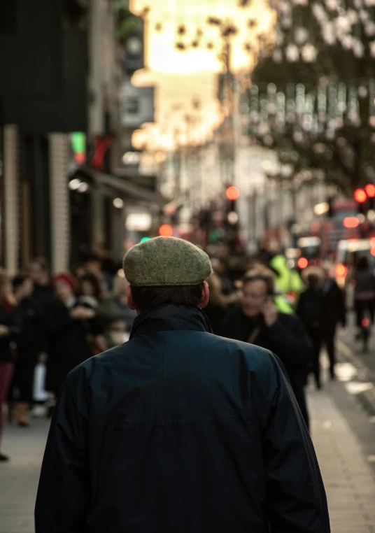 a man wearing a hat looks up at people on the street