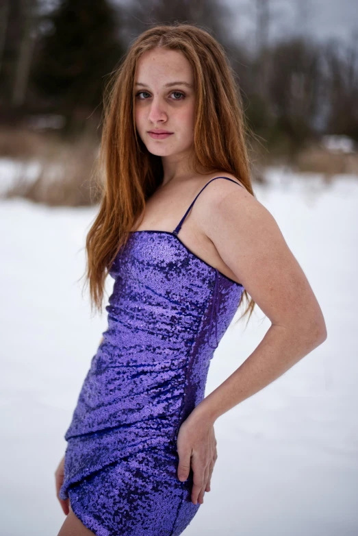 a  posing on the snow in her purple dress