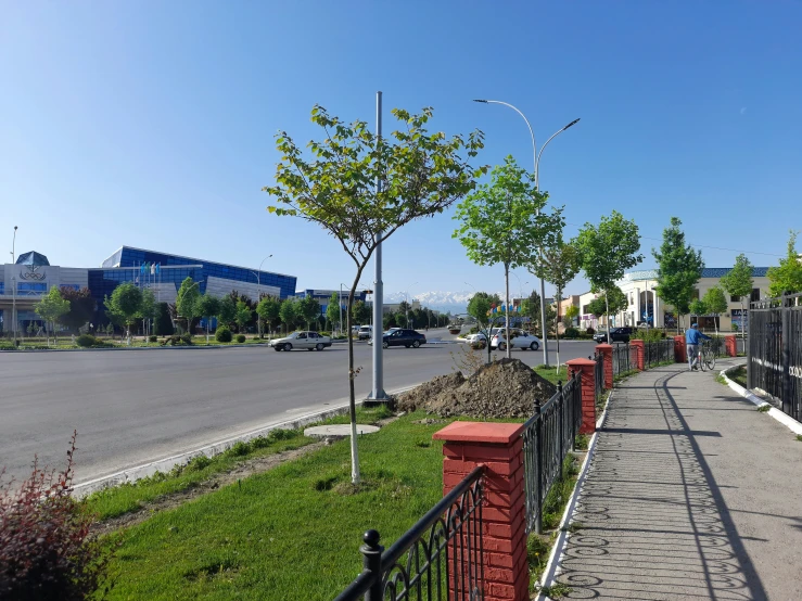 a road is quiet with a fence near a street and a red wall