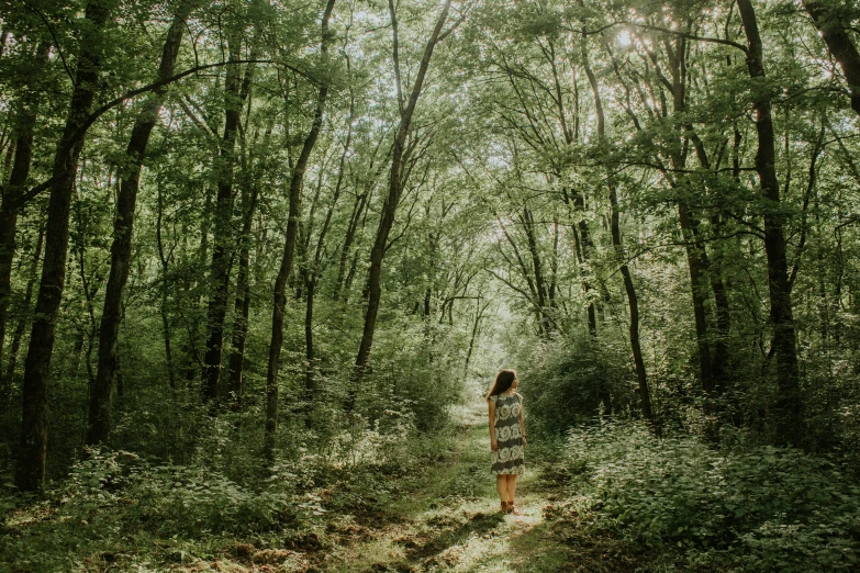 a woman walking through a lush green forest