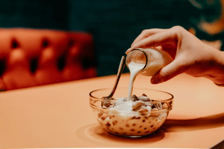 a person pouring milk into a bowl on top of a table