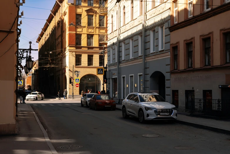 three cars sit at the street near tall buildings