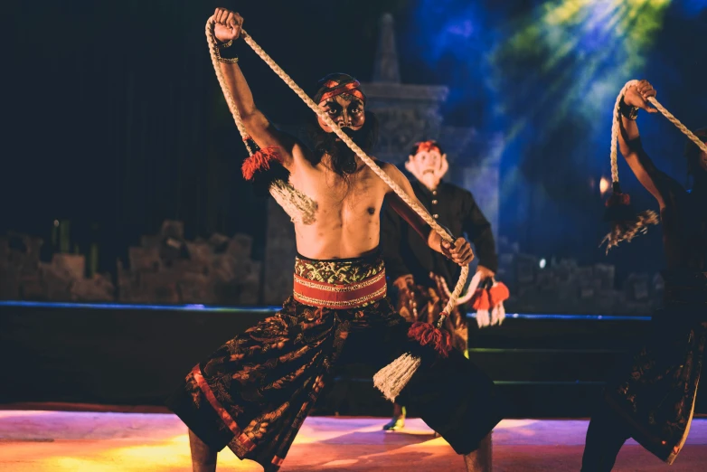 two men and a woman dancing in a tribal dance