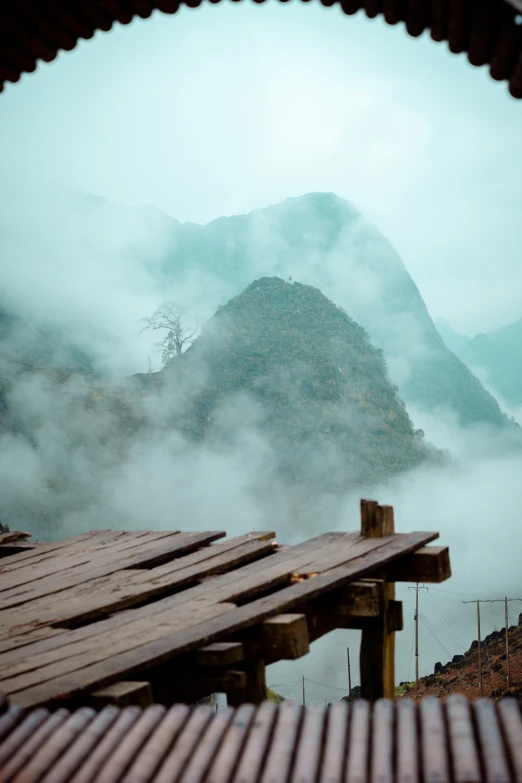 a bench overlooks mountains with a misty sky