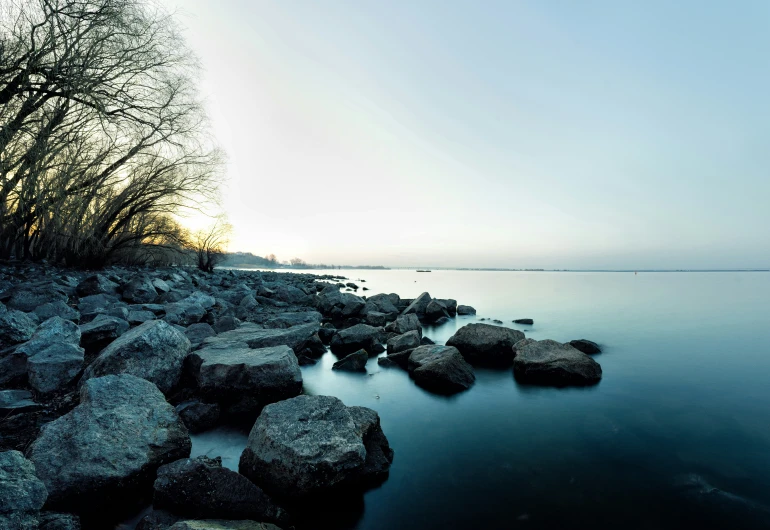 the shore line has rocks along it and some trees on both sides