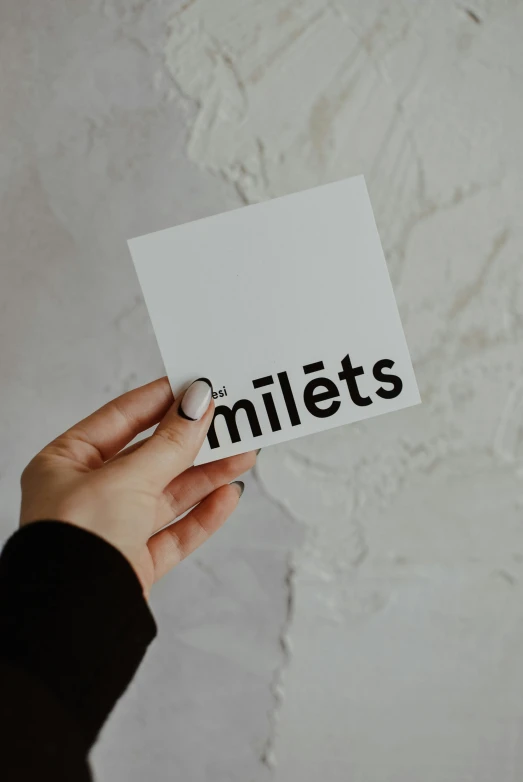 a woman holding a piece of paper with the word miles printed on it