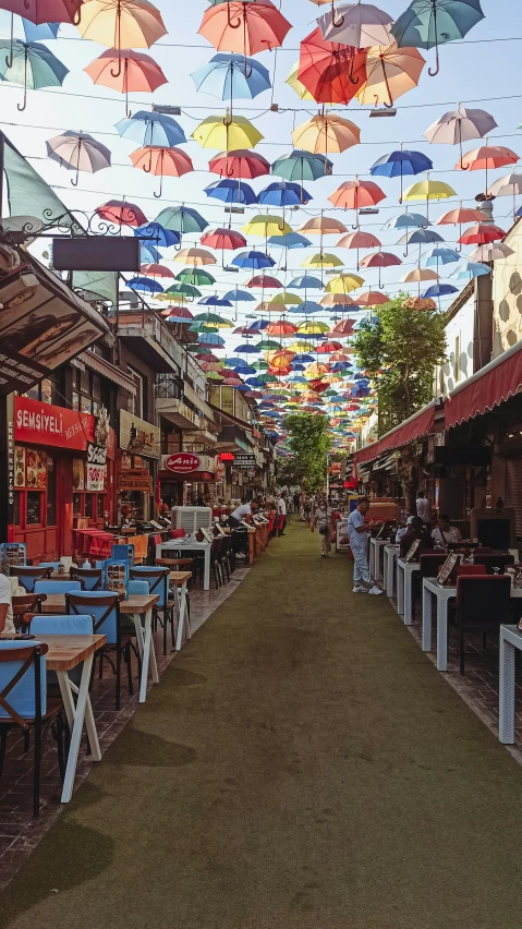 a lot of umbrellas hang in the air above tables and chairs