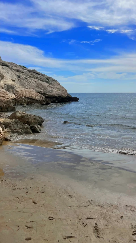 a beach with an ocean and rocks in the background