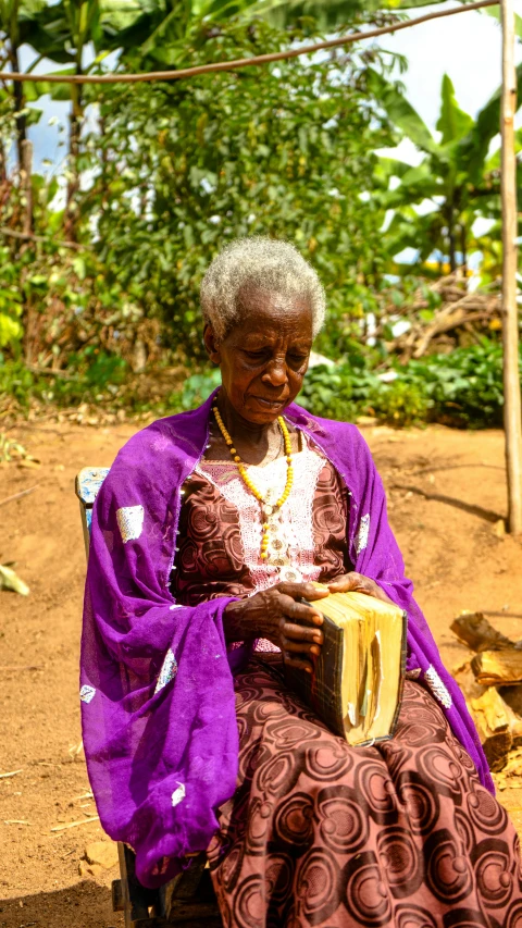 a woman sitting outside holding a small instrument