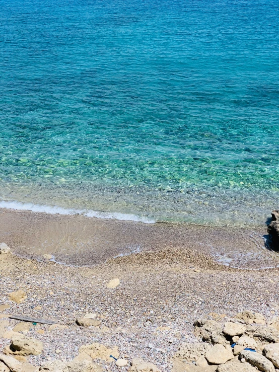 two people sit on the beach looking out over water