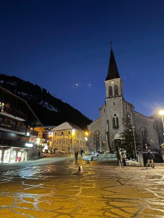 the town is lit up at night and features a gothic style tower with pointed tops