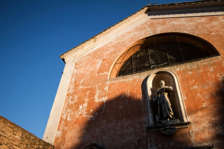 the sun is shining on a building that has a statue and a cross