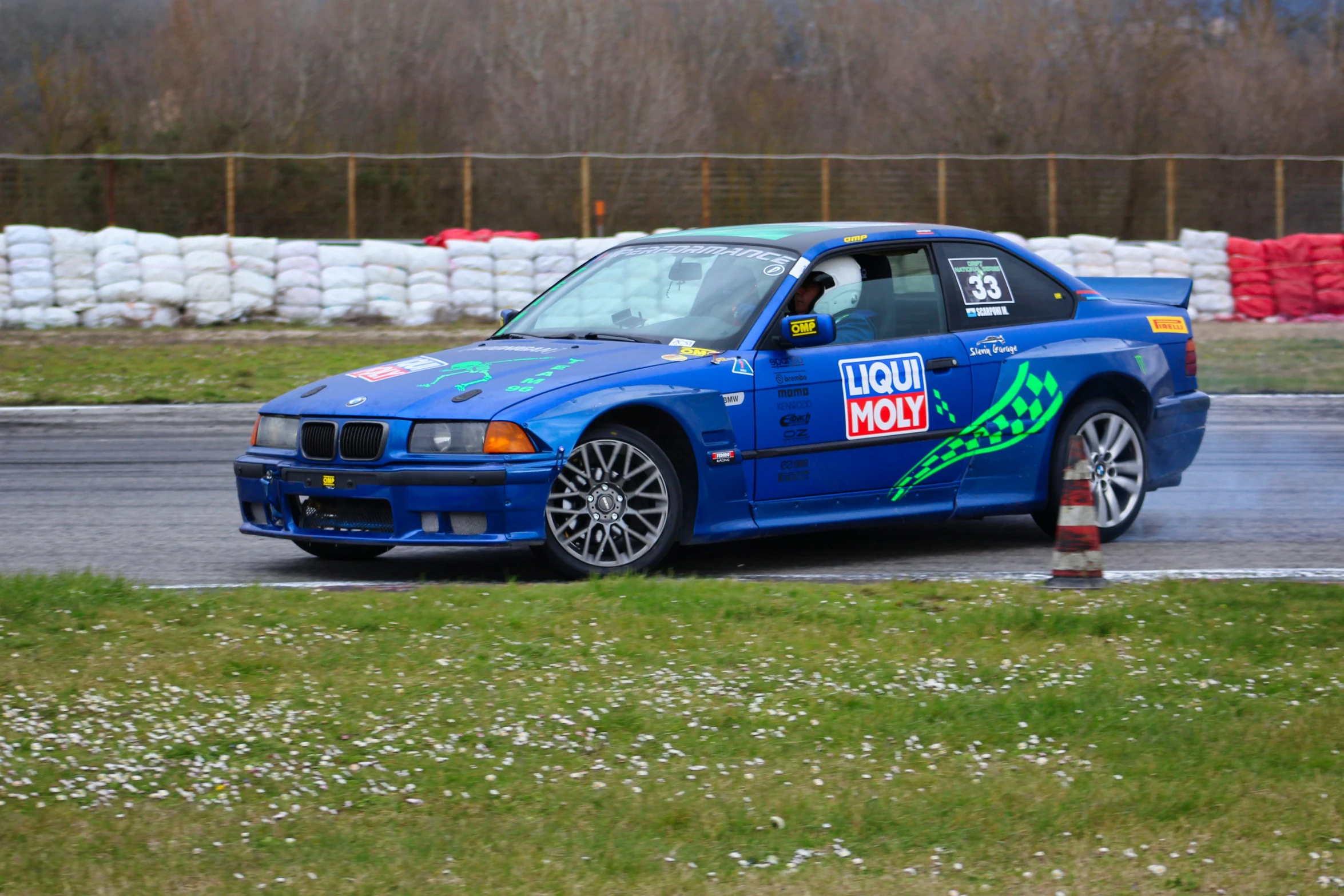 a blue car driving down a wet track