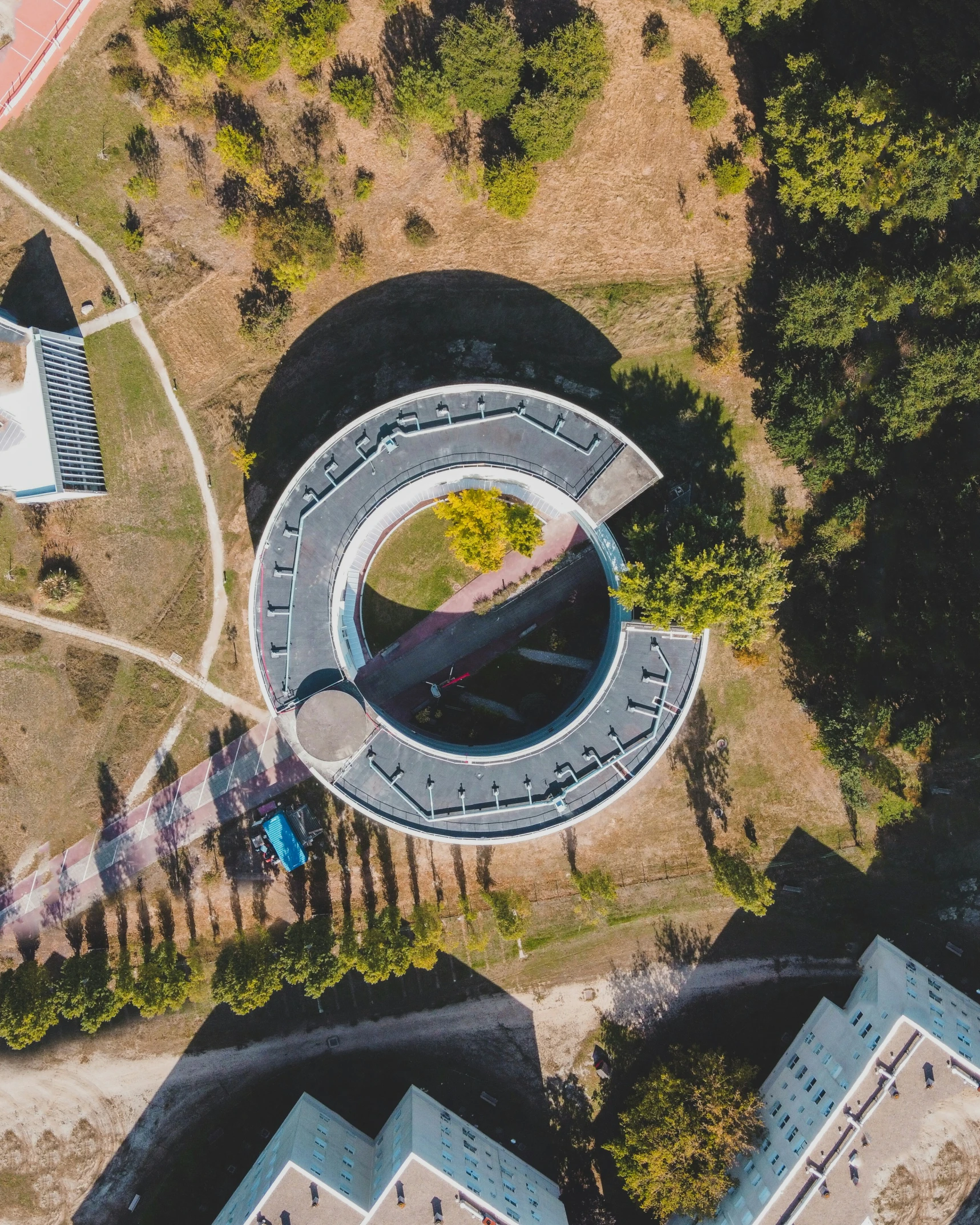 the aerial view shows a circular building surrounded by forest