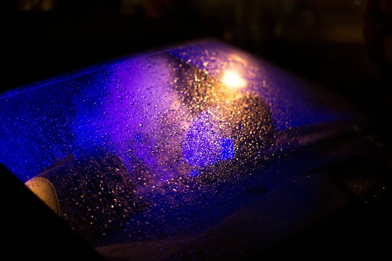 a wet window with a blurry view of it at night