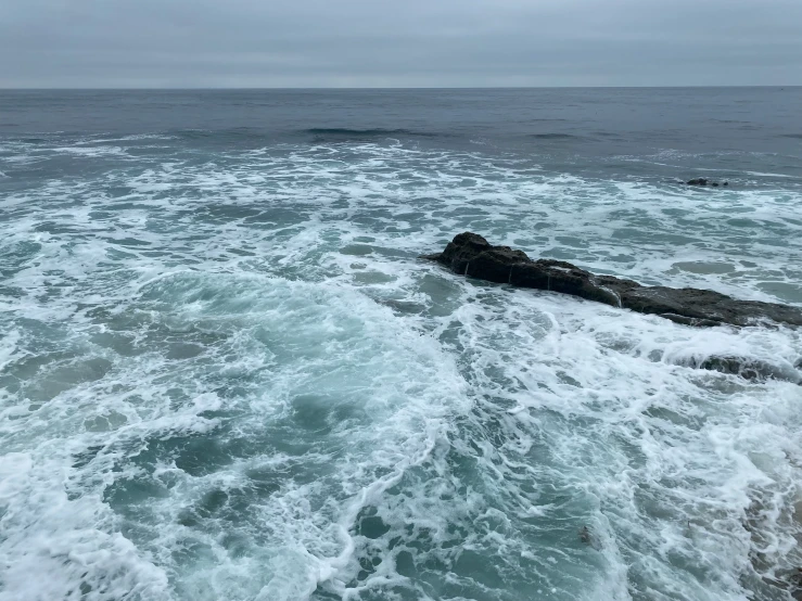 the water is choppy and white as it crashes at the coast