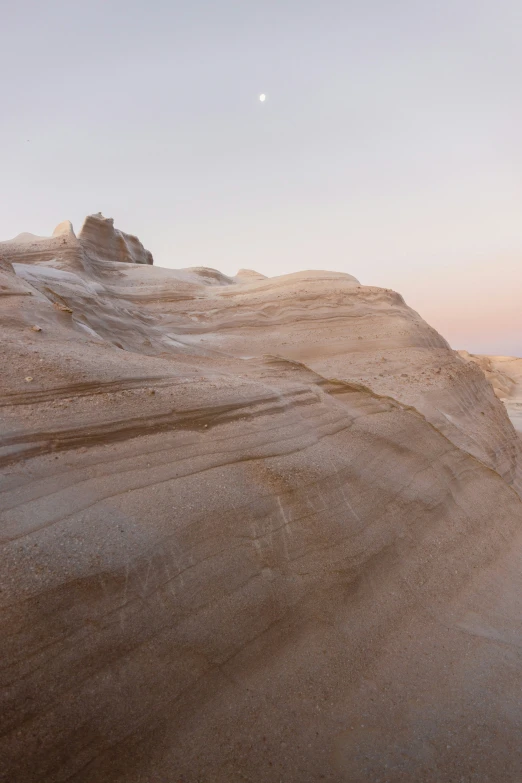 sand dunes with a lone object near them at sunset