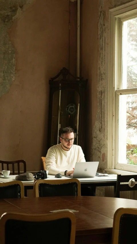 a man in a white sweater using a laptop computer