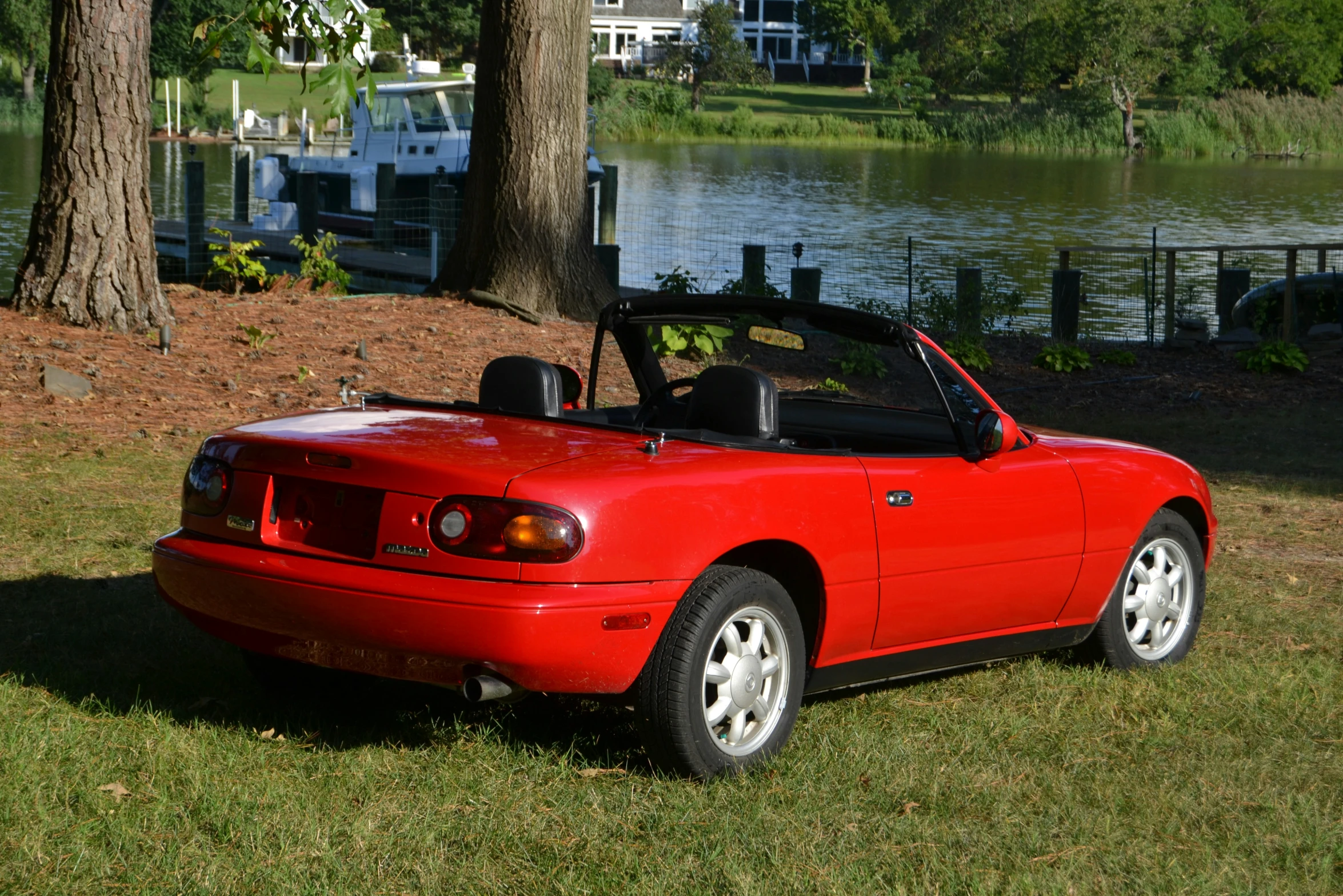 the red convertible convertible is parked in front of a lake