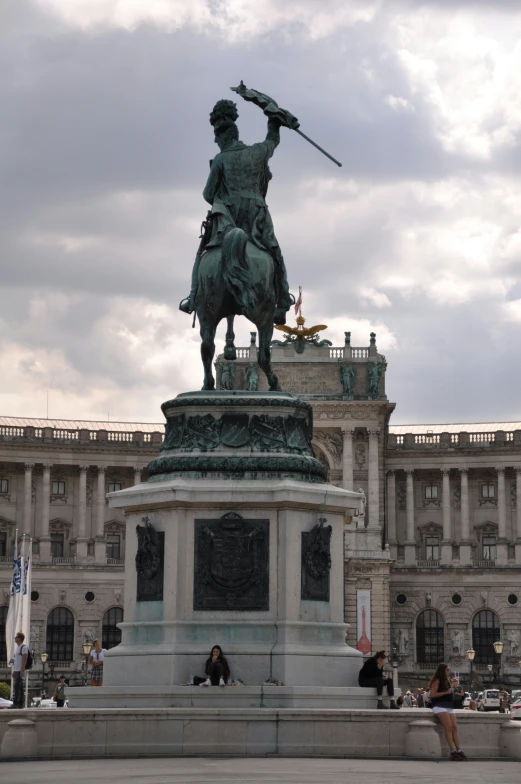 a statue in the middle of a square with many people walking around