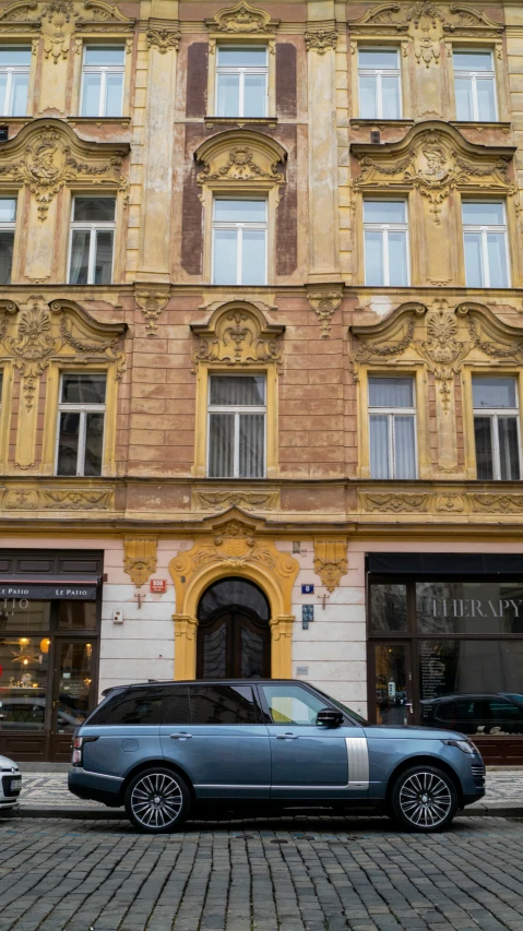 a blue car parked in front of an old fashioned building