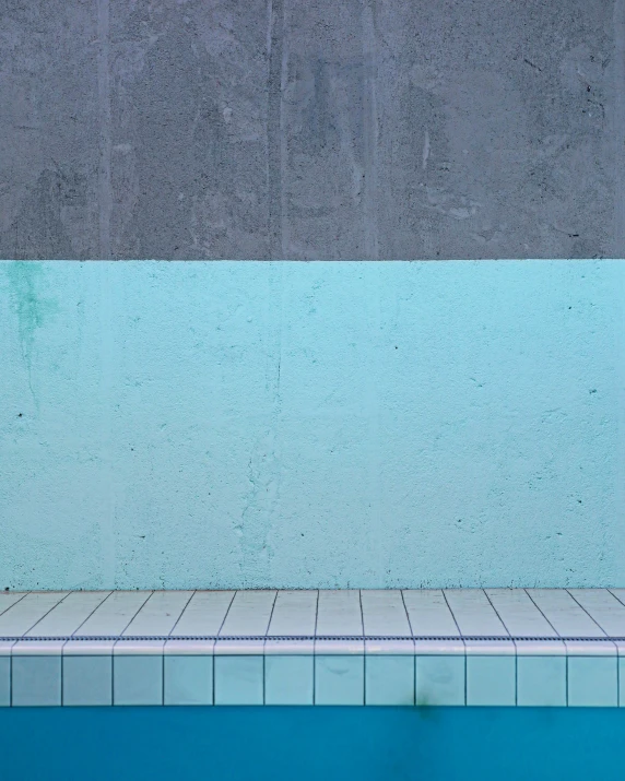 there is a swimming pool with white tiles on it