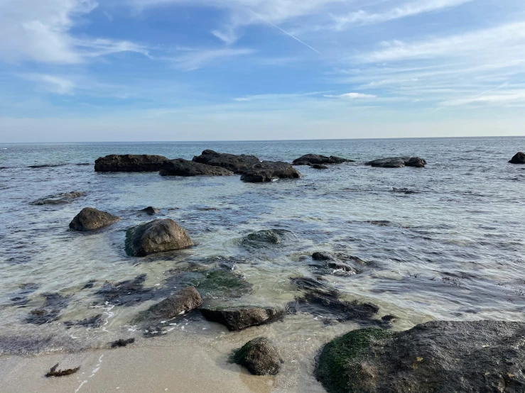 a kite is being flown over the water by rocks