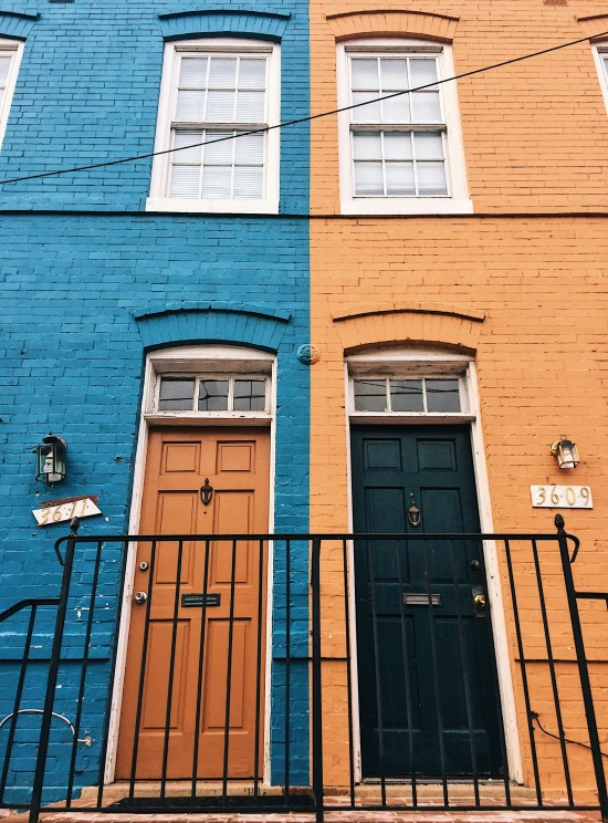 two multicolored doors in front of a fence