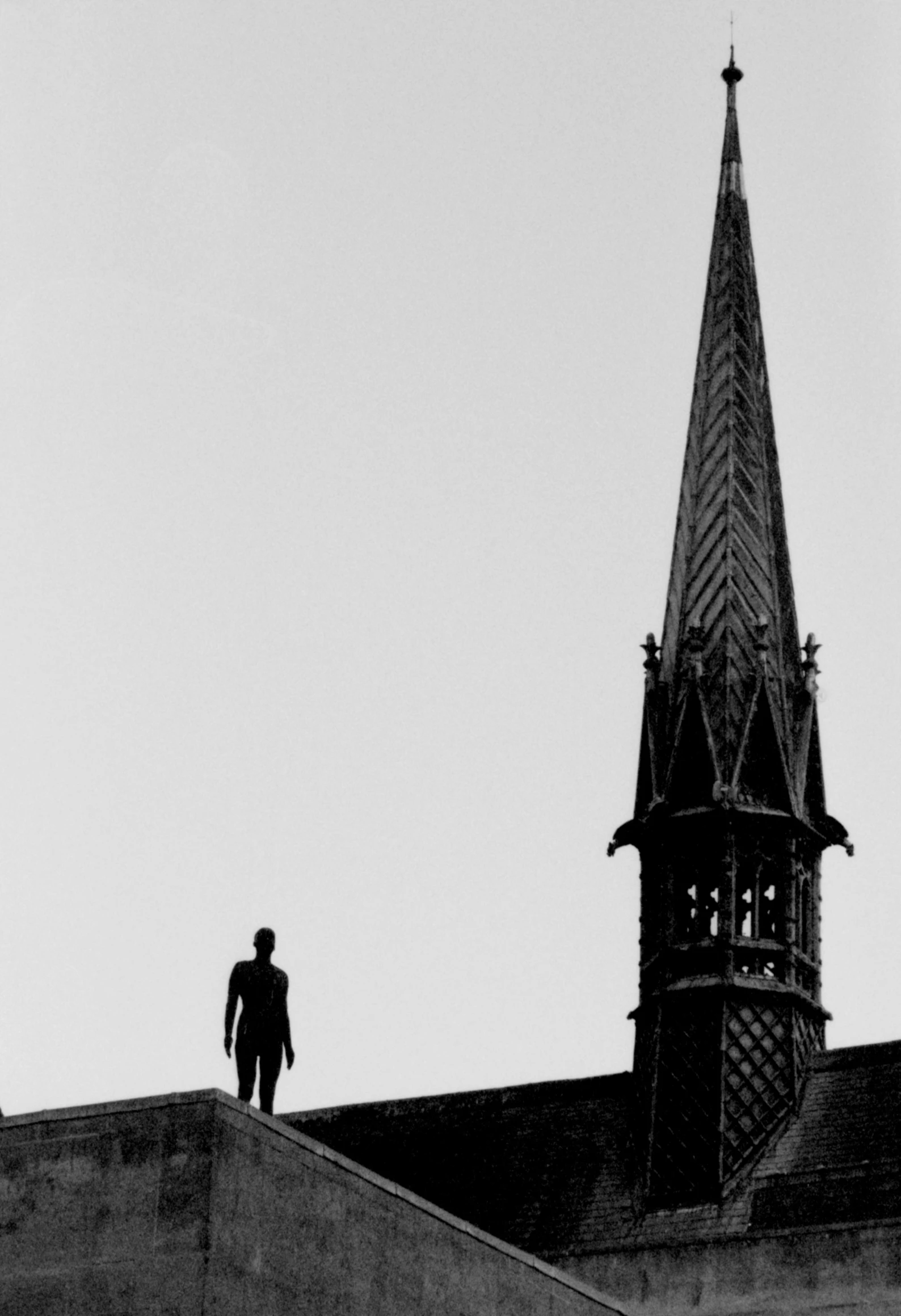 a black and white image of a person at the top of a church