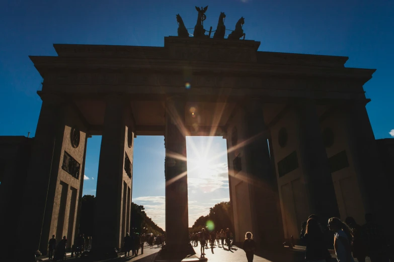 the sun shines brightly down over a large arch in a courtyard