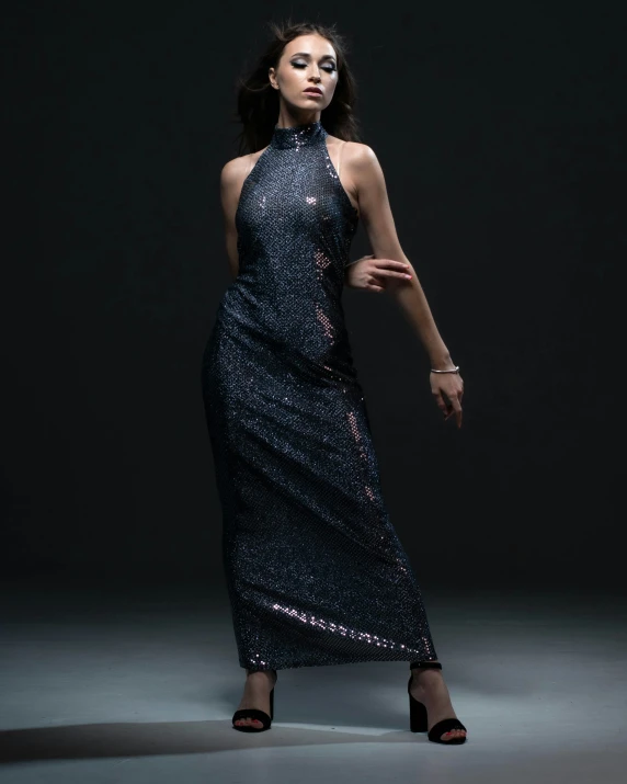 a woman wearing an evening gown poses in front of a dark background