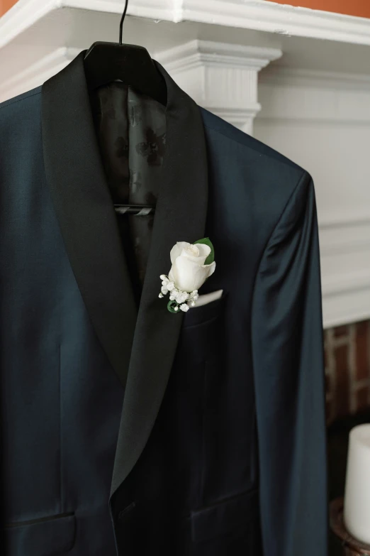a black jacket with white flower and brooch hangs