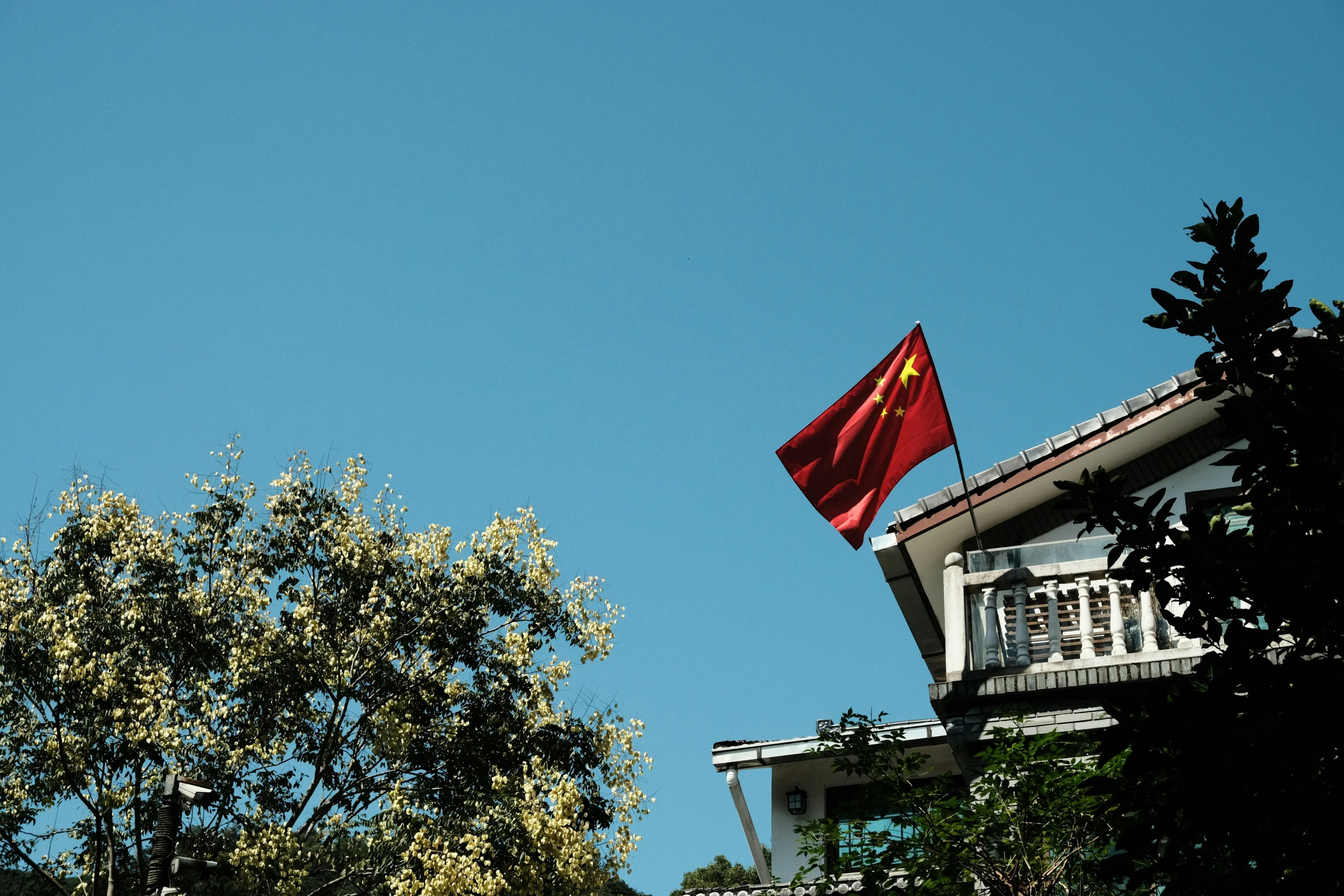 a big red flag hanging from a roof of a house