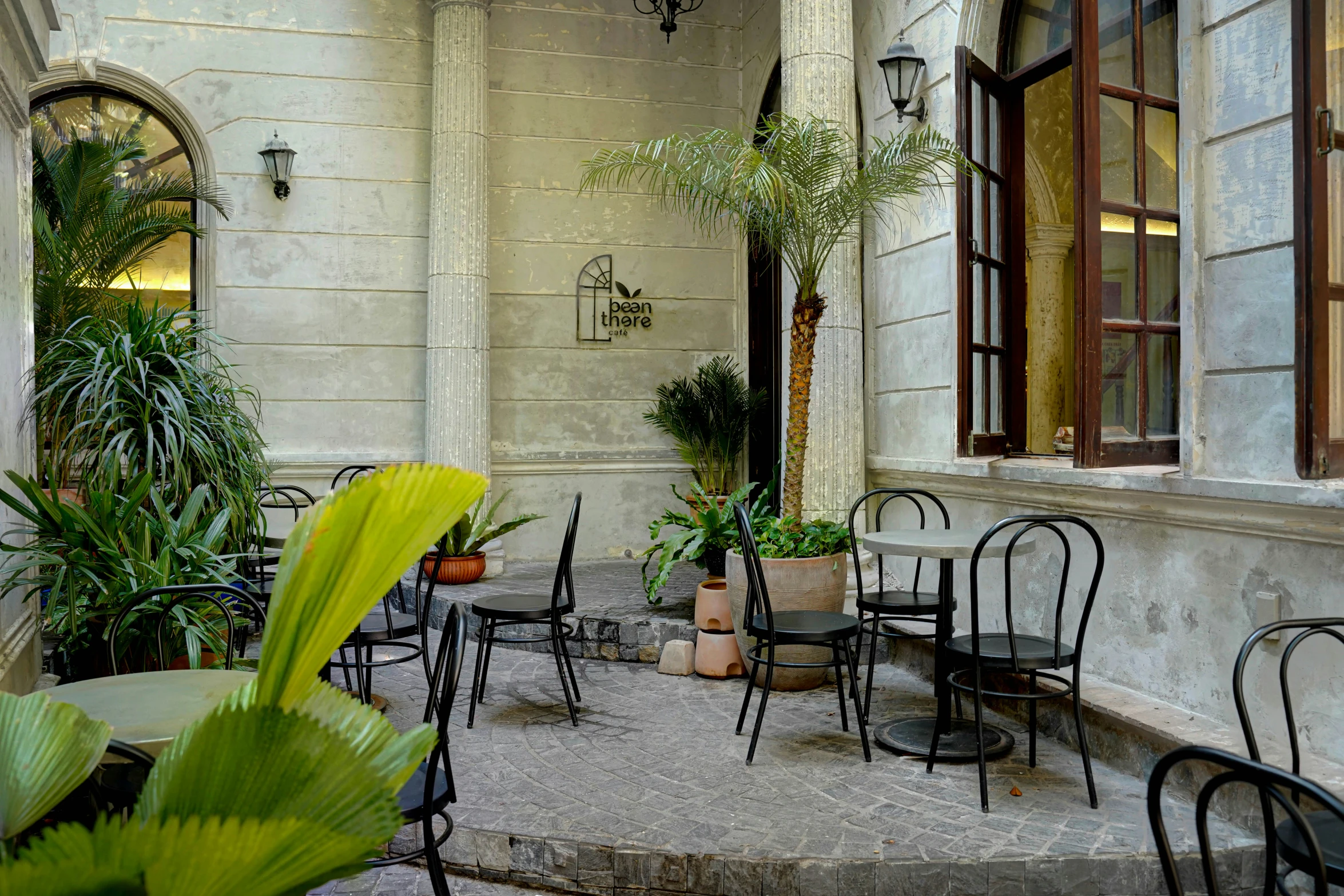 a patio in front of a building with many tables and chairs and lots of plants