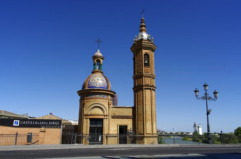 large tan building with clocks on its sides and a blue sky