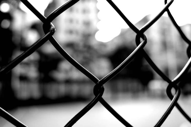 a close up of a metal fence with a building in the background