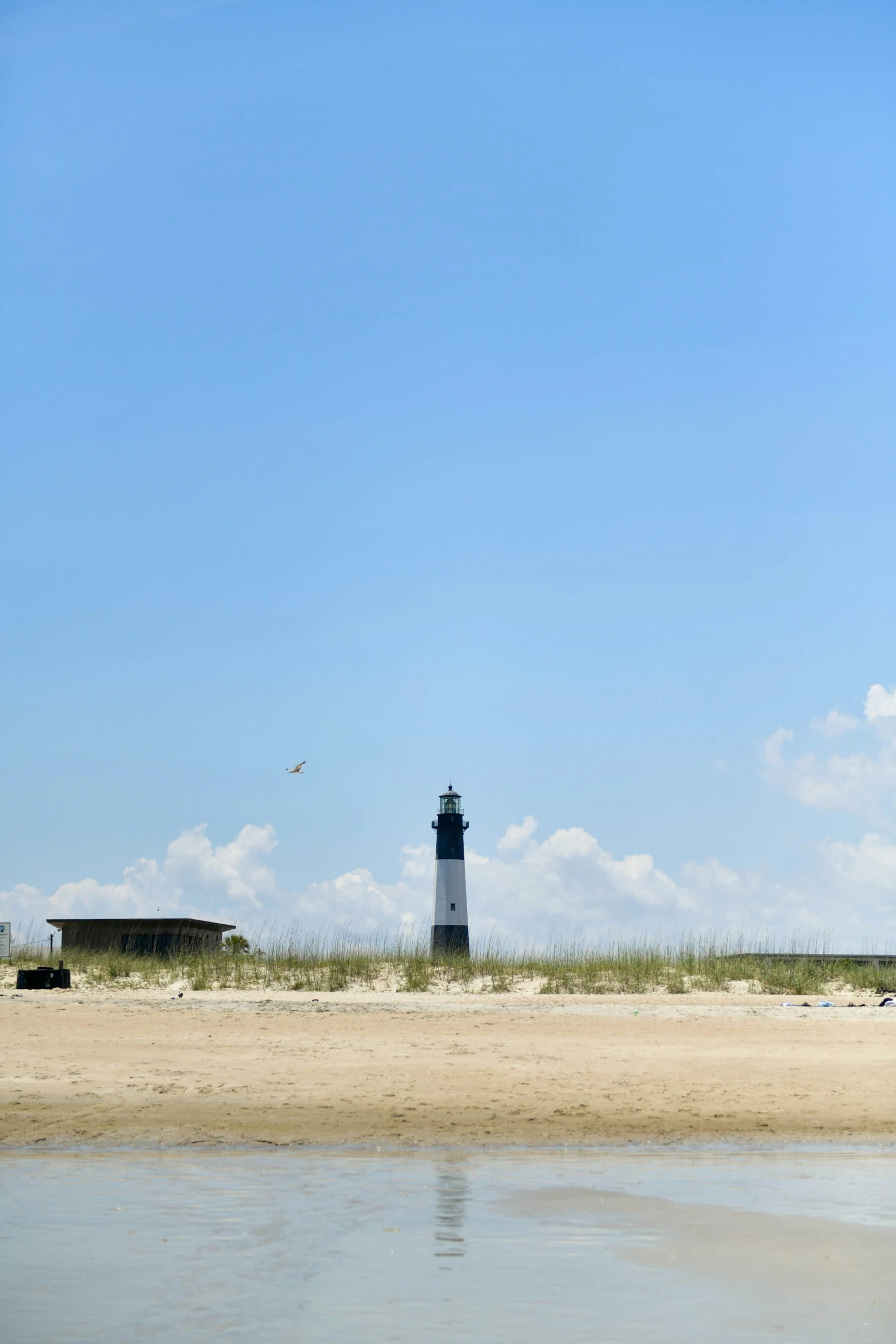 the beach has a lighthouse on it with a blue sky in the background