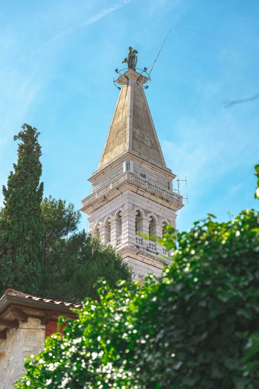 an ornate clock tower sitting behind a leafy tree